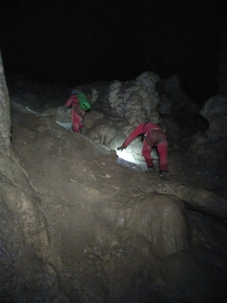 2 spéléos remontent une pente dans une grande salle