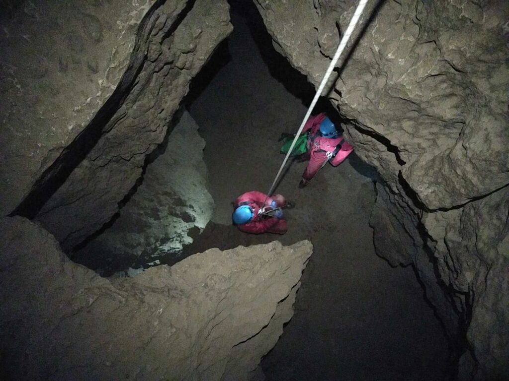 2 spéléologues sont en bas d'un puits. Un d'eu remonte la corde.