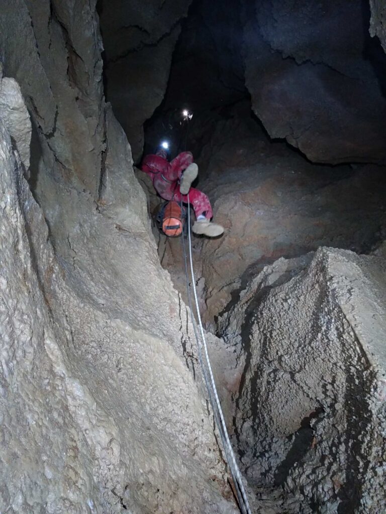 Un spéléo descend un puits à l'aide d'une corde